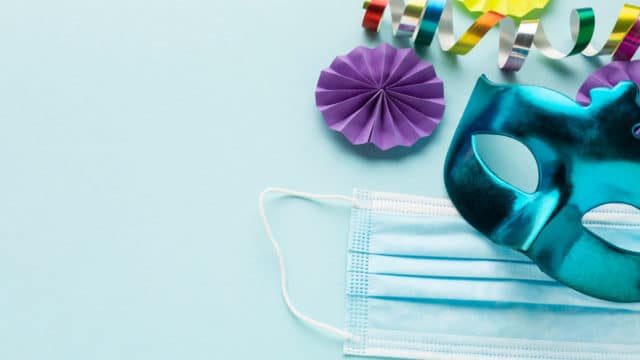 Máscara descartável ao lado de enfeites e máscara de carnaval.