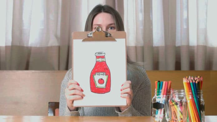 Uma mulher segurando seu desenho do Ketchup Heinz na campanha 