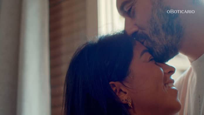 Um homem beijando a testa de uma mulher. Cena da campanha de O Boticário retratando histórias reais de amor.