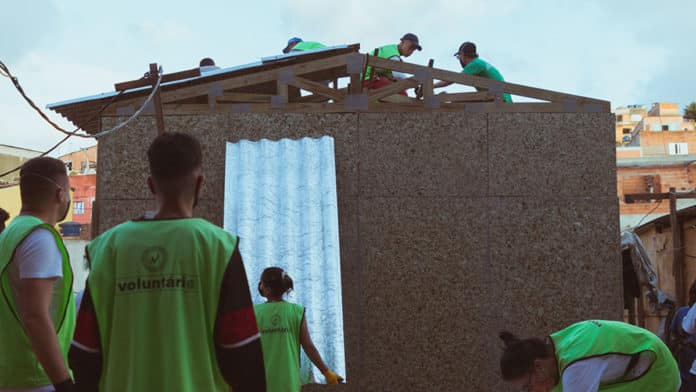 Voluntários ajudando na construção dos telhados feitos a partir de telhas recicladas das caixas de sucos Do Bem.
