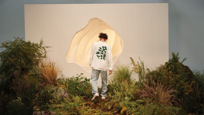 Jaden Smith para a campanha de sustentabilidade da Levi's. Na foto aparece Jaden de costas em meio a um cenário com algumas plantas e um fundo branco.
