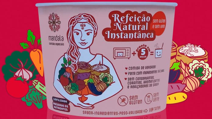 Foto de divulgação da linha de Refeições Naturais Instantâneas da Mandala. Na foto, uma embalagem do produto, e ao fundo vários vegetais desenhados contrastando com um fundo rosa.