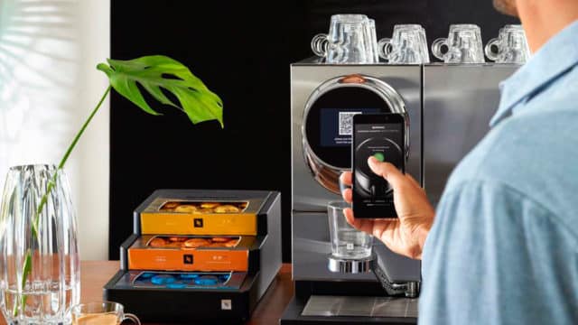 Um homem ativando a nova máquina de café da Nespresso com um celular.