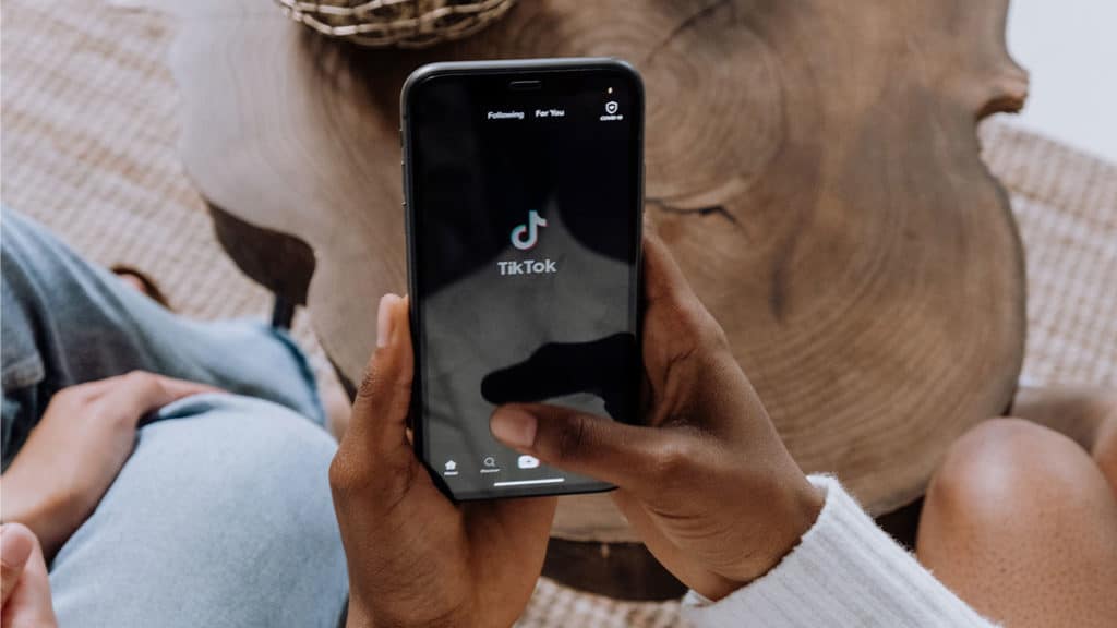 Uma pessoa segurando um celular aberto no TikTok, app agora com legendas automáticas.