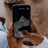 Uma pessoa segurando um celular aberto no TikTok, app agora com legendas automáticas.