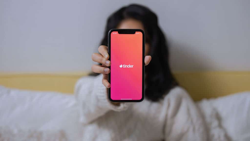 Uma mulher segurando um celular aberto no Tinder, app da ferramenta Passaporte.
