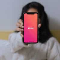 Uma mulher segurando um celular aberto no Tinder, app da ferramenta Passaporte.