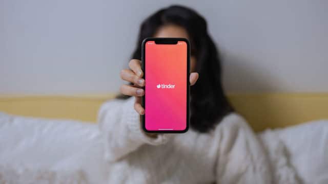 Uma mulher segurando um celular aberto no Tinder, app da ferramenta Passaporte.