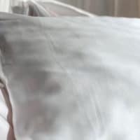 Foto de divulgação da coleção de fronha de Dia dos Namorados da FOREO e Scarf Me. A foto apresenta um travesseiro com fronha branca em uma cama com roupa de cama branco.