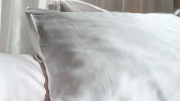 Foto de divulgação da coleção de fronha de Dia dos Namorados da FOREO e Scarf Me. A foto apresenta um travesseiro com fronha branca em uma cama com roupa de cama branco.
