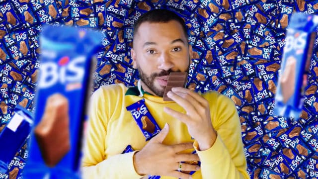 Nova campanha de Bis Xtra com Gil do Vigor. A foto apresenta o Gil deitado em meio a um monte de Bis Xtra, enquanto cai mais chocolate em cima dele e come um dos tabletes.