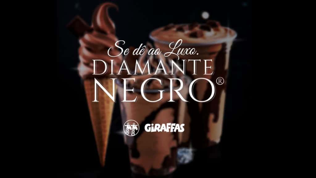 A foto apresenta as sobremesas de Diamante Negro do Giraffas ao fundo e desfocado, com uma frase na frente escrito: Se dê ao luxo, com o logo das marcas.