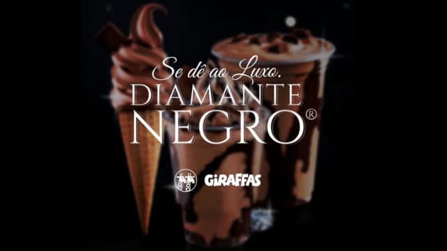 A foto apresenta as sobremesas de Diamante Negro do Giraffas ao fundo e desfocado, com uma frase na frente escrito: Se dê ao luxo, com o logo das marcas.