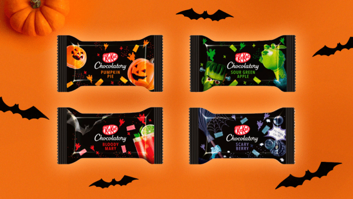A foto apresenta os 4 sabores de KitKat de Halloween com um fundo laranja cheio de morcegos espalhados e uma abóbora no canto superior esquerdo.