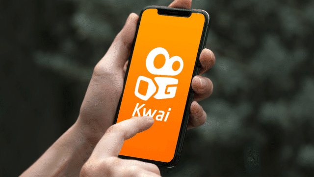A foto apresenta uma pessoa abrindo o app Kwai para representar a nova plataforma de anúncios da rede social.