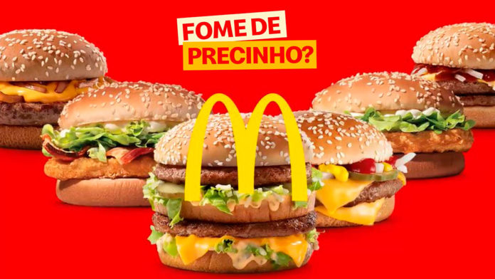 A foto apresenta os sanduíches do Clássicos do Dia em um fundo vermelho, com o logo do McDonald's e do Fome de Precinho.