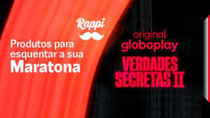 A foto apresenta um banner preto e laranja com o logo do Rappi, da Globoplay e da novela convidando o consumidor a maratonar Verdades Secretas 2 com os produtos selecionados.