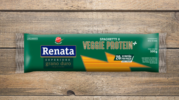 A foto apresenta a embalagem do novo Macarrão Renata Superiore Veggie Protein +, em cima de uma mesa de madeira.