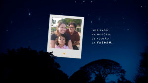 A foto apresenta a cena final da campanha da Lacta sobre o Natal de crianças adotadas, em que mostra uma foto da protogonista do filme com a sua família.