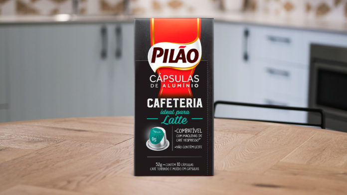 A foto apresenta a cápsula Pilão ideal para Latte em cima de uma mesa de madeira, em meio a uma cozinha.