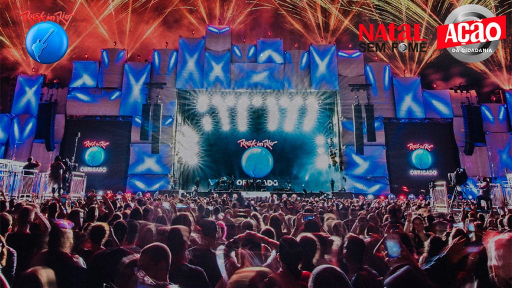 A foto apresenta um dos palcos do Rock in Rio com seu público e os logos das marcas e da campanha do sorteio de ingressos nos cantos superiores da imagem.