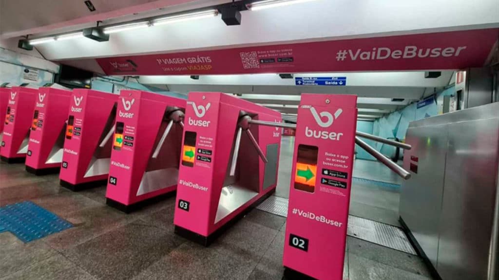 A foto apresenta as catracas do metrô com a invasão rosa da Buser.