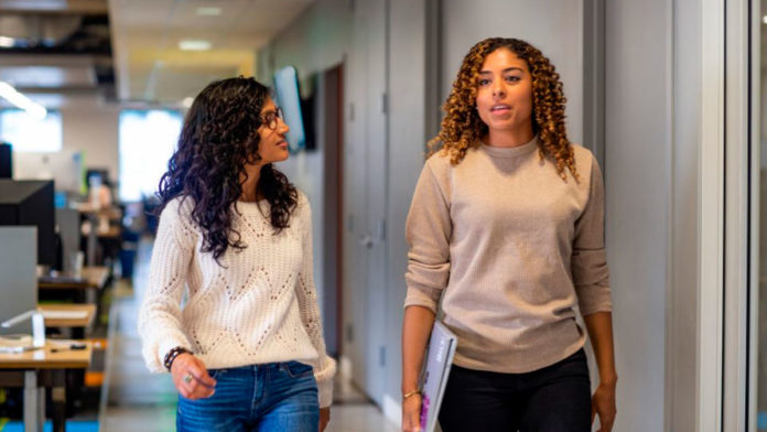 Foto de duas mulheres com pastas na mão em um corredor, representando o #GirlsPower da Microsoft.