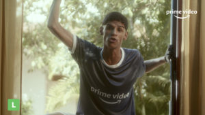 Iran Ferreira, conhecido como Luva de Pedreiro, aparece pendurado em uma janela vestindo uma camiseta do Prime Video