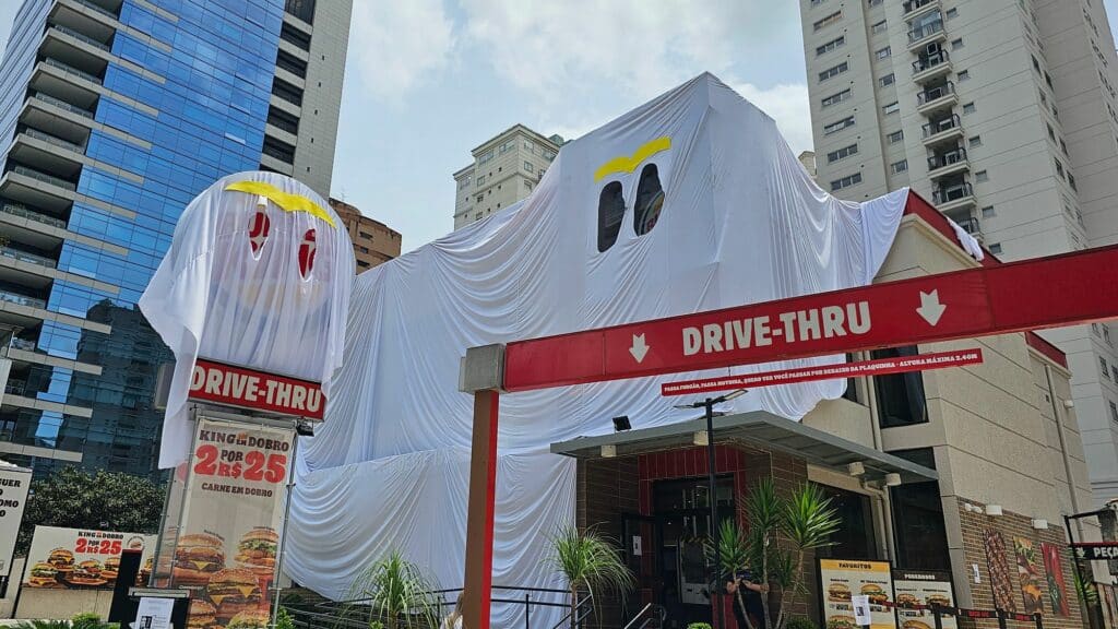 Foto da fachada do Burger King coberta por um pano branco para simular uma fantasia de fantasma para o Halloween.