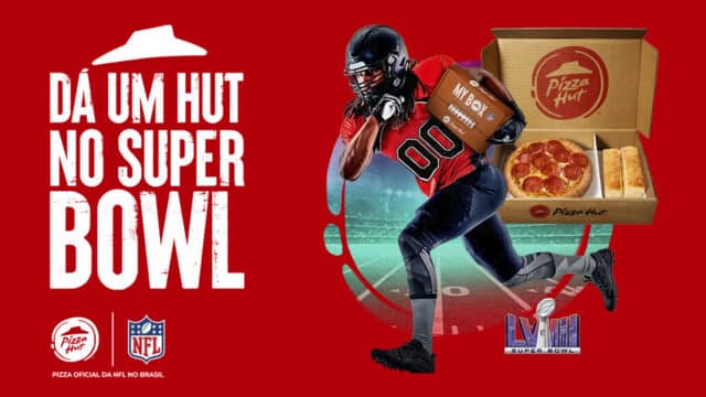 Imagem mostra logo da promoção onde se lê "Dá um hut no super bowl". Ao lado é possível ver um jogador de futebol americano com uma caixa de pizza nas mãos. Ao lado também há uma caixa de pizza aberta onde se vê uma pizza e dois acompanhamentos breadsticks.