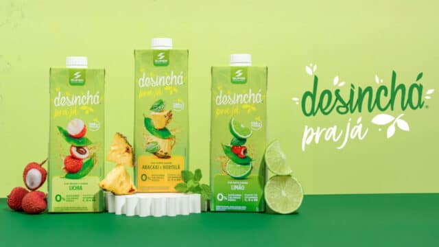 Imagem com o logo da linha "Desinchá Pra Já" juntamente com as embalagens dos sabores Chá Mate com Limão, Chá Verde com Abacaxi e Hortelã, e Chá Branco com Lichia