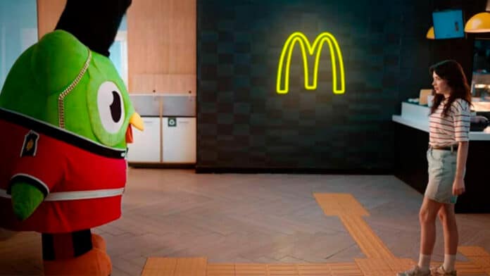 Captura de tela de um trecho do filme que será exibido mostrando o Duolingo em uma loja do McDonald's de frente para a consumidora que está com problemas na pronúncia de McFish and Chips