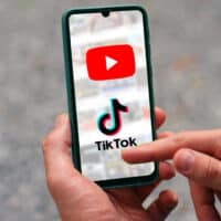 Imagem de um celular mostrando o logo do YouTube e do TikTok