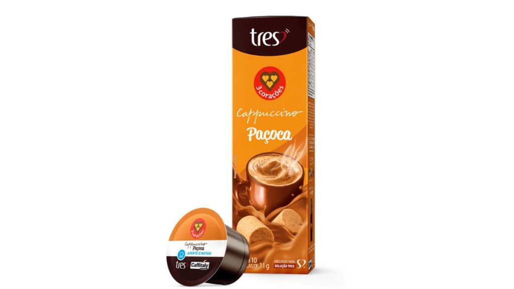 Embalagem do Cappuccino sabor Paçoca da 3 Corações, com um copo de cappuccino e biscoitos ao fundo.