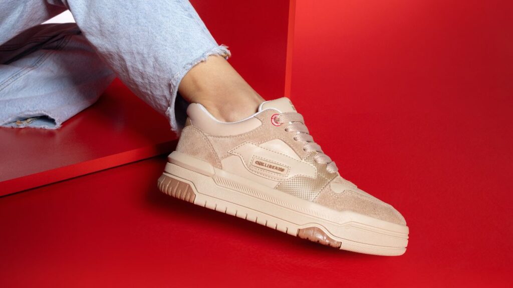 Tênis Chilli Sneakers em tom claro, posicionado sobre fundo vermelho, com detalhes de design urbano.