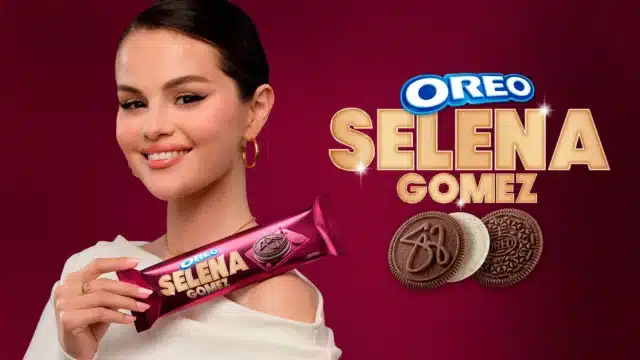 Imagem promocional de Selena Gomez segurando um pacote de biscoitos Oreo, com o texto 'OREO SELENA GOMEZ' ao fundo em letras grandes.