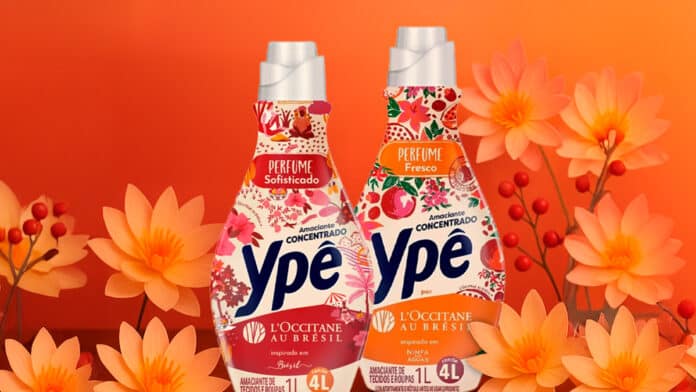 Embalagens de amaciantes concentrados da Ypê em colaboração com a L'Occitane Au Brésil, apresentando as fragrâncias 'Perfume Sofisticado' e 'Perfume Fresco', decoradas com flores e um fundo laranja.