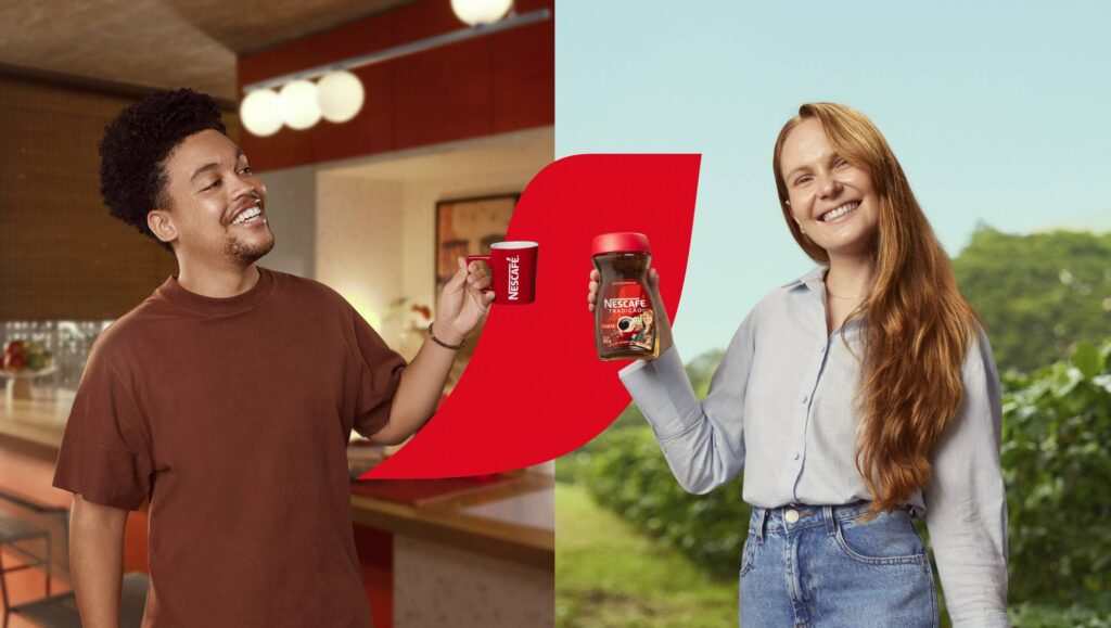 Imagem de duas pessoas sorrindo, uma segurando uma xícara vermelha da Nescafé e a outra segurando um pote de café Nescafé, em um cenário que combina um ambiente interno e uma vista de campo ao fundo.