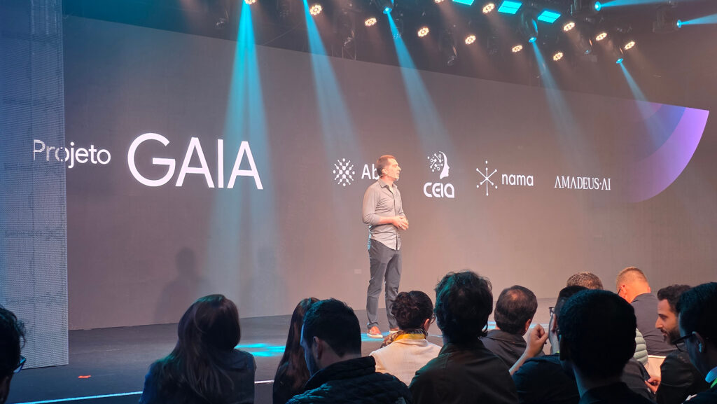 Apresentação do Projeto GAIA em evento do Google, com um palestrante no palco e telas de fundo exibindo o nome do projeto e logos de parceiros.