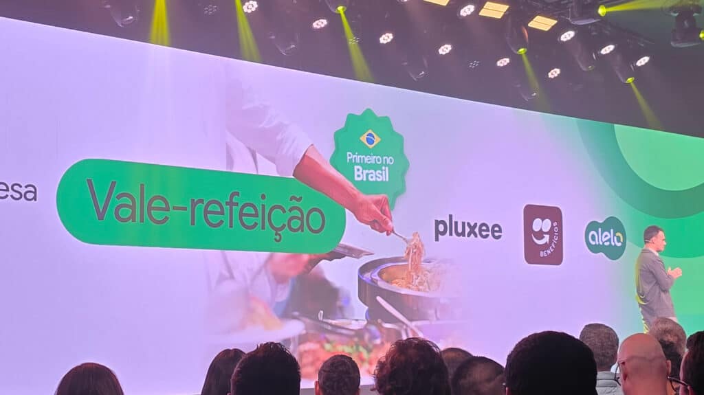 Apresentação durante o evento Google For Brasil, destacando a parceria com plataformas de vale-refeição, com uma imagem de uma pessoa servindo comida ao fundo e logos das empresas parceiras.