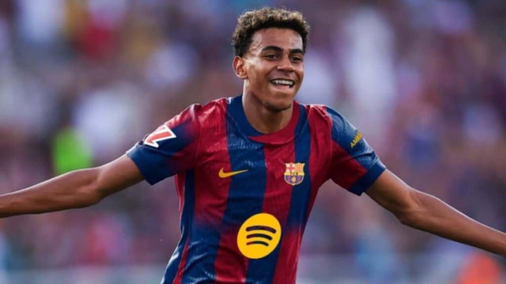 Jogador do Barcelona sorrindo e comemorando com a nova camisa do clube, que apresenta as cores azul e grená.