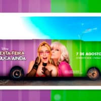 Ônibus adesivado com arte de divulgação do filme "Uma Sexta-Feira Mais Louca Ainda", da Disney. O veículo está dividido em duas cores: a metade esquerda em roxo e a direita em verde. No lado roxo, aparecem os dizeres "Uma Sexta-Feira Mais Louca Ainda" e o logo da Rádio Disney 91.3. Ao centro, há uma imagem das protagonistas do filme, uma jovem loira de óculos rosa e uma mulher mais velha com cabelo branco e expressão divertida. No lado verde, lê-se "7 de agosto – Somente nos cinemas". Ao fundo, céu azul e parte de uma rua urbana.