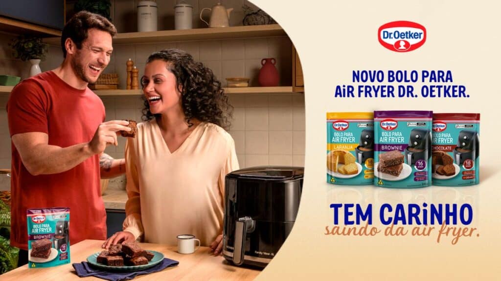 Casal sorridente compartilhando um pedaço de bolo em uma cozinha aconchegante, com vários produtos da linha de bolos para Air Fryer da Dr. Oetker em destaque.
