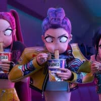 Mira, Rumi e Zoey desfrutando de macarrão instantâneo, com expressões concentradas e envolvidas, em um trecho do filme Guerreiras do K-Pop da Netflix.