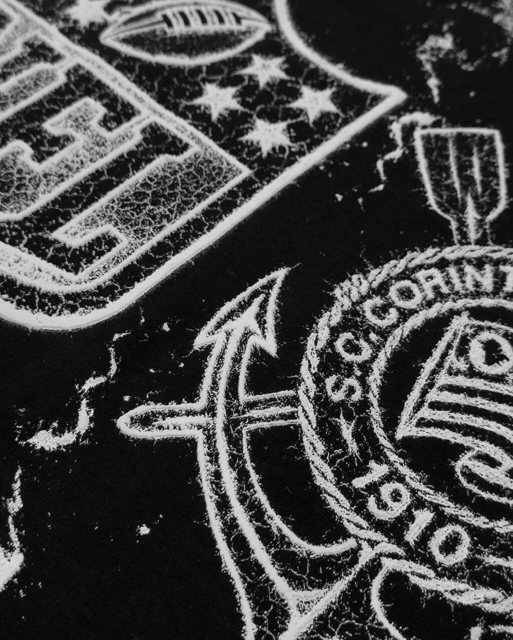 Detalhe de uma camiseta que apresenta os logos da NFL e do Corinthians, com um design em preto e branco.