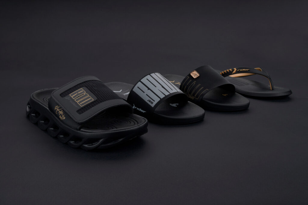 Imagens dos modelos de sandálias da collab Rider + R10, incluindo um modelo com a assinatura de Ronaldinho Gaúcho, em fundo preto.