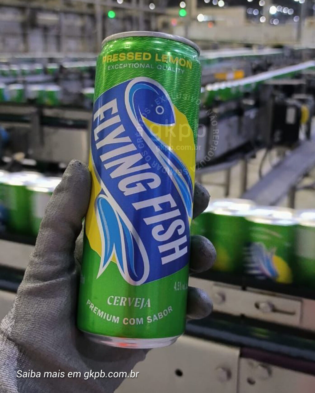 Lata de cerveja Flying Fish sendo segurada, destacando o rótulo colorido com a descrição 'Pressed Lemon' e 'Cerveja Premium com Sabor', em um ambiente de produção.