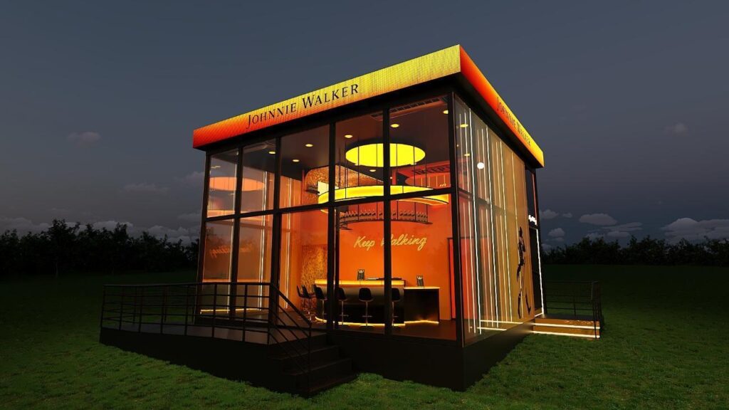 Vista exterior do estande da Johnnie Walker, com design moderno e iluminação laranja, durante o festival The Town 2025.