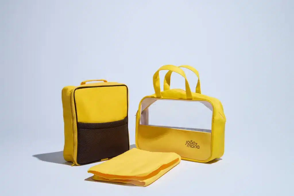 Conjunto de bolsas amarelas da linha João e Maria, incluindo uma bolsa com janela de visualização e um suporte para itens.