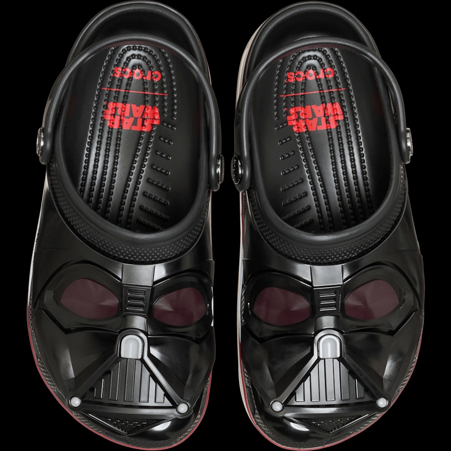 Clogs da Crocs temáticas do Darth Vader, com design preto e detalhes vermelhos, incluindo o sabre de luz dos Sith e a máscara icônica.